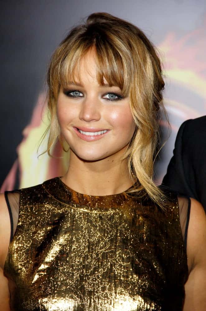 Jennifer Lawrence's lovely golden dress was quite the complement to her messy bun hairstyle with loose tendils and side-swept bangs at the Los Angeles premiere of 'The Hunger Games' held at the Nokia Theatre L.A. Live in Los Angeles on March 12, 2012.