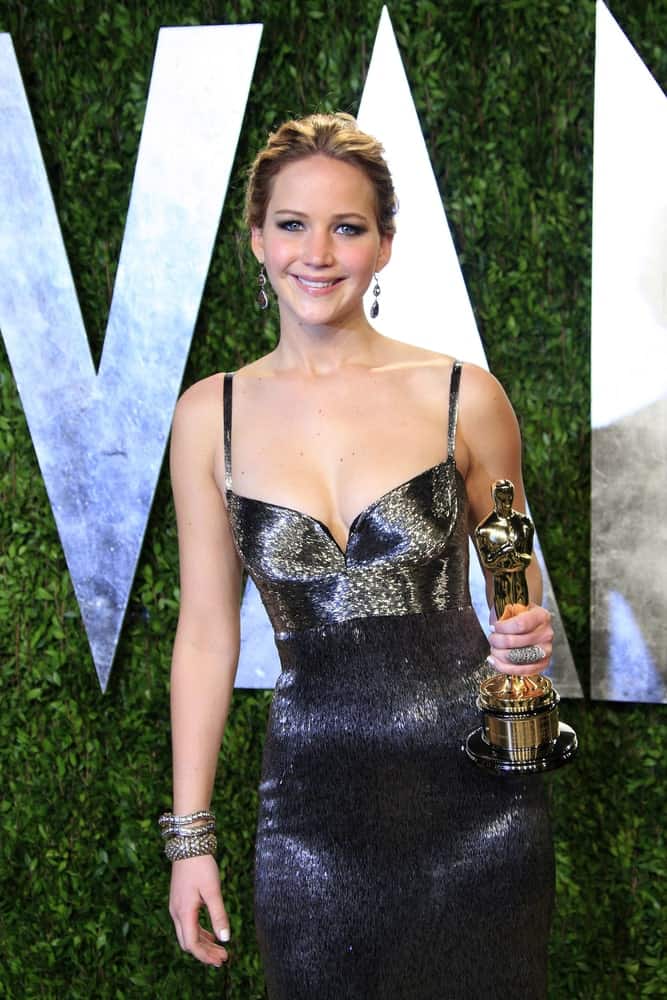 Jennifer Lawrence flashed her beautiful smile as she held her Oscar trophy at the Vanity Fair Oscar Party at Sunset Tower on February 24, 2013 in West Hollywood, California. She wore a black dress to pair with her simple slicked-back bun hairstyle.