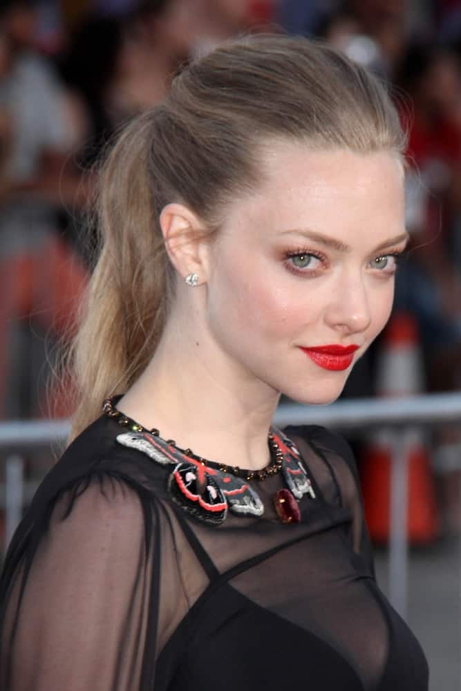 Amanda Seyfried's sheer black outfit and bold red lips are complemented by her lovely messy ponytail hairstyle with a slight tousle at the 