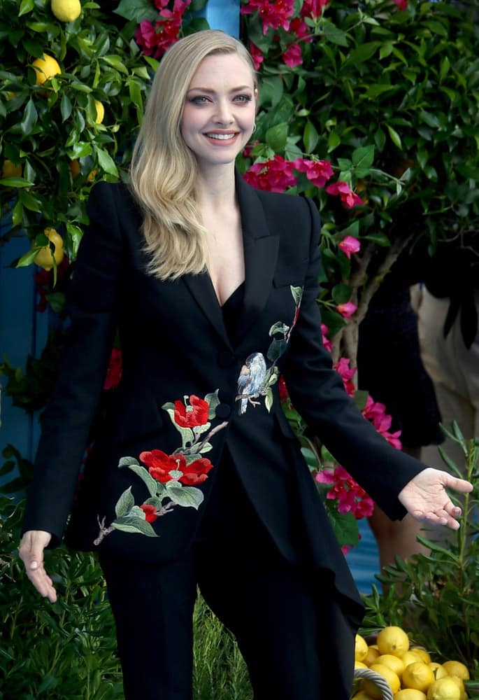Amanda Seyfried attended the Mamma Mia! Here We Go Again film premiere on July 16, 2018 in London. She came wearing a black suit with embroidered flowers that she paired with a long and side-swept blond hairstyle with layered waves at the tips.