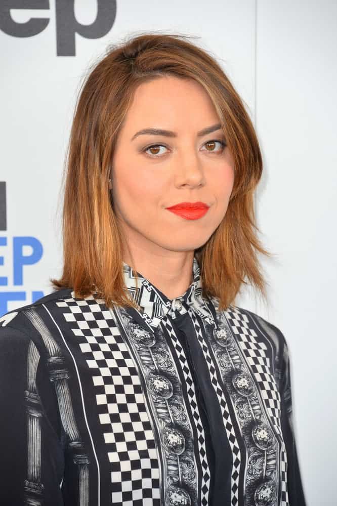 On February 25, 2017, Aubrey Plaza attended the 2017 Film Independent Spirit Awards on the beach in Santa Monica. She wore a black and white dress that she paired with her shoulder-length layered brunette hairstyle with side-swept bangs.