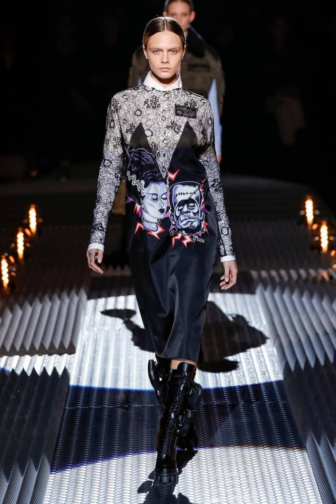 Cara Delevingne walked the runway at the Prada show at Milan Fashion Week Autumn/Winter 2019/20 on February 21, 2019 in Milan, Italy. She was dressed in a fashionable dress with black leather boots and a slick center-parted hairstyle.