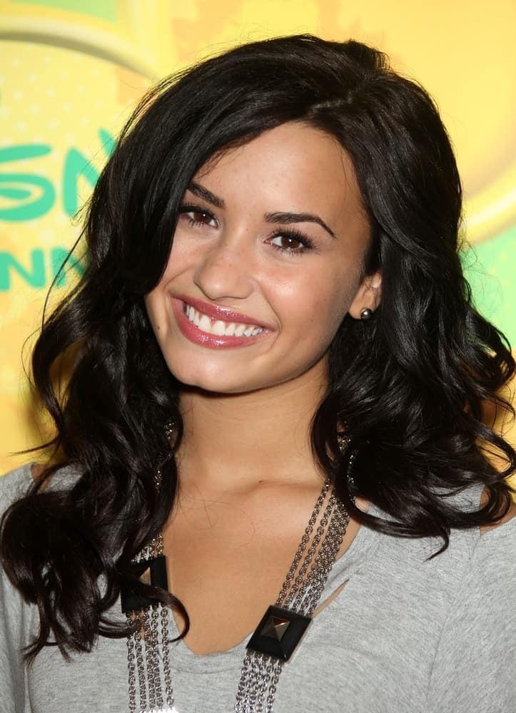 Demi Lovato was at the Disney|ABC Television Group Summer Press Junket on May 15, 2010 in Burbank, CA. She wore a simple gray outfit to pair with her medium-length tousled raven wavy hairstyle incorporated with long side-swept bangs.