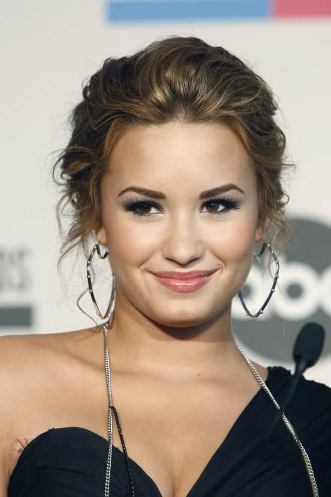 Demi Lovato paired her lovely black dress with a messy upstyle that has loose highlighted tendrils at the 2010 American Music Awards Nominations Press Conference at The Mixing Room - JW Marriott on October 12, 2010 in Los Angeles, CA.