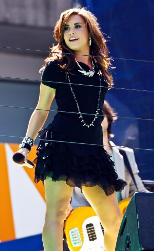 Singer Demi Lovato performed at the Arthur Ashe Kids' Day at the Billie Jean King National Tennis Center on August 28, 2010 in Flushing, New York. She wore a short black dress with her long and tousled highlighted layers with a brunette brown tone.