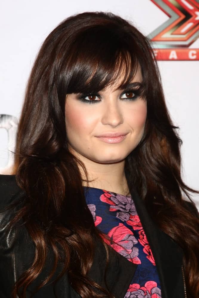 Demi Lovato paired her beautiful smokey eyes with a long and loose wavy dark brown hairstyle incorporated with eye-skimmer bangs and layers when she arrived at the X Factor 2012 Final Four Party at Rodeo Drive on December 6, 2012 in Beverly Hills, CA.