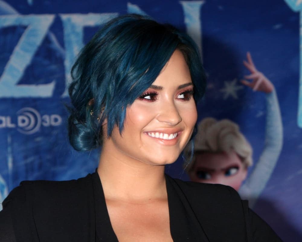 Demi Lovato was at the "Frozen" World Premiere at the El Capitan Theater on November 19, 2013 in Los Angeles, CA. She paired her lovely black outfit with a cool blue-toned messy low bun hairstyle with tousled side-swept bangs that has layers.