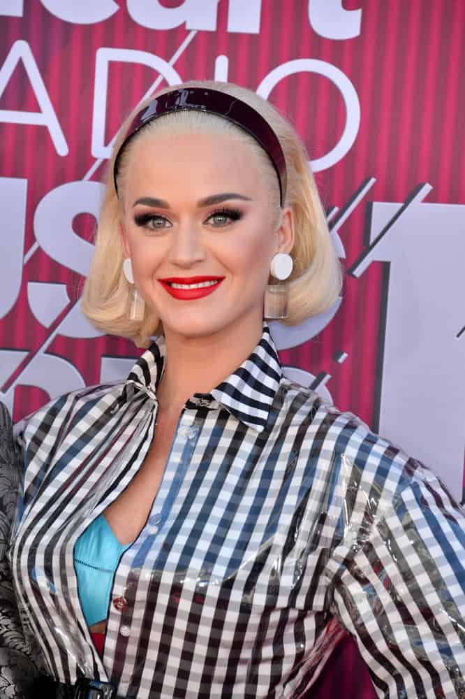 Katy Perry slicked back her short blonde hair with a black headband during the 2019 iHeartRadio Music Awards at the Microsoft Theatre on March 14, 2019. Statement earrings and a plaid top completed the vintage look.