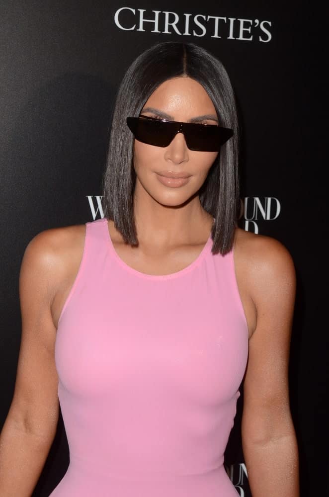 Kim Kardashian looking sleek in her bob cut that's complemented with black shades and a pink dress at the Christie's X 25th Anniversary Auction Preview at the What Goes Around Comes Around on August 21, 2018.
