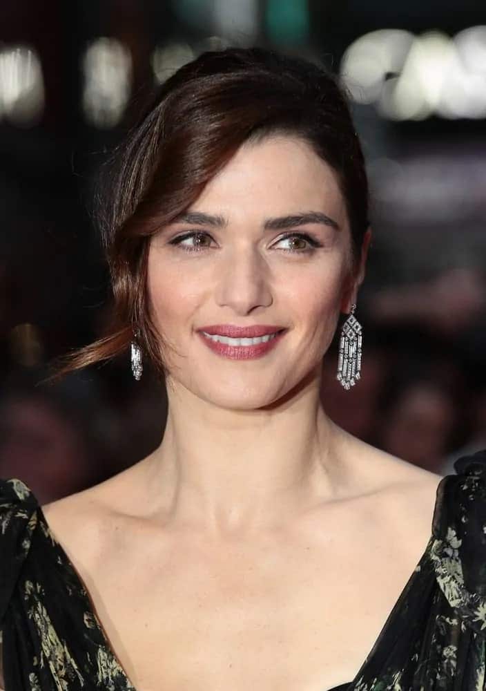 Rachel Weisz wears an elegant black floral gown with her gorgeous brunette locks in a pulled back upstyle with curly side parting as she attends the Lobster premiere on October 12, 2015.
