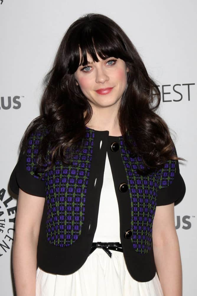 Zooey Deschanel was at the "New Girl" Panel at PaleyFest 2012 at the Saban Theater on March 5, 2012 in Los Angeles, CA. She was charming in a white dress and cardigan to pair with her long and tousled wavy raven hairstyle that has layers and bangs.