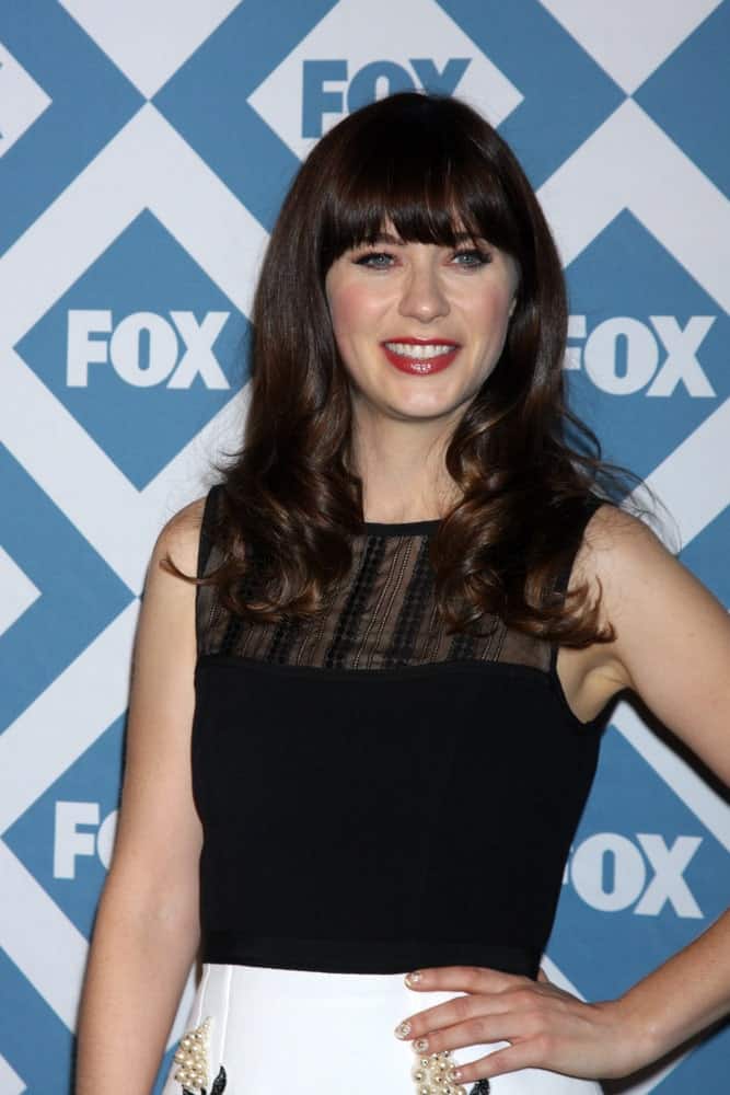 Zooey Deschanel was at the FOX TCA Winter 2014 Party at Langham Huntington Hotel on January 13, 2014 in Pasadena, CA. She wore a simple black and white dress with her long and curly dark brunette hairstyle that is loose and tousled with blunt bangs.