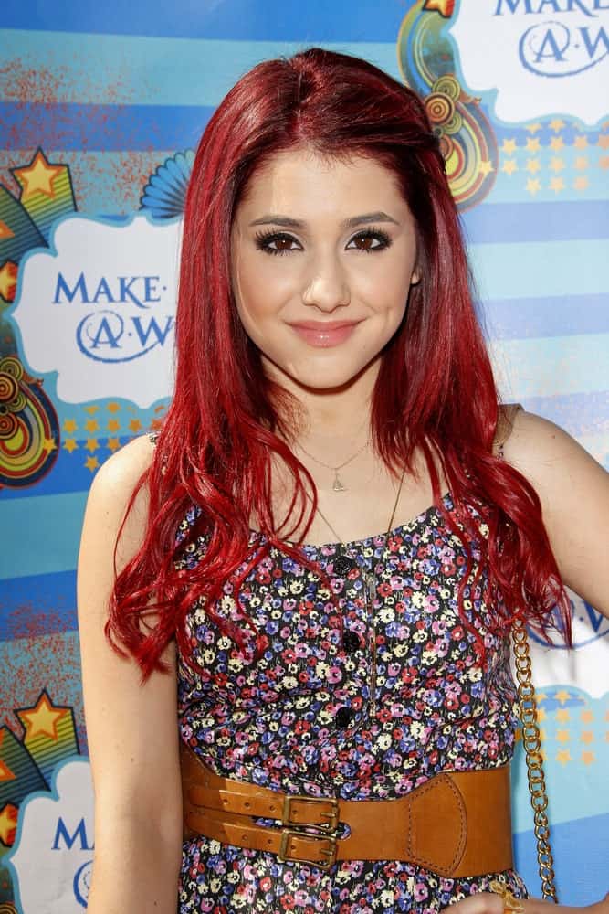 Ariana Grande arrived at the Kevin + Steffiana James + Make-A-Wish Foundation Host A Day of Fun on March 14, 2010, wearing a floral button front romper. She styled her red hair with a pin on one side and subtle waves at its ends for a dramatic look.