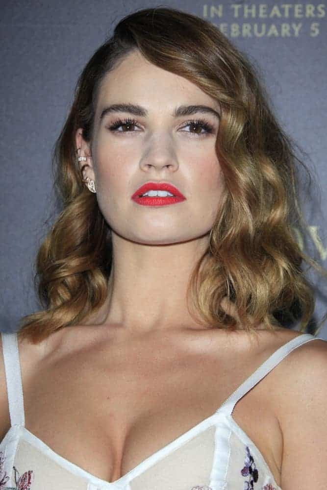 Lily James was at the Pride And Prejudice And Zombies Premiere at the Harmony Gold Theatre on January 21, 2016, in Los Angeles, CA. She was charming in a white dress that she paired with red lips and curly brunette shoulder-length hairstyle with side-swept bangs.
