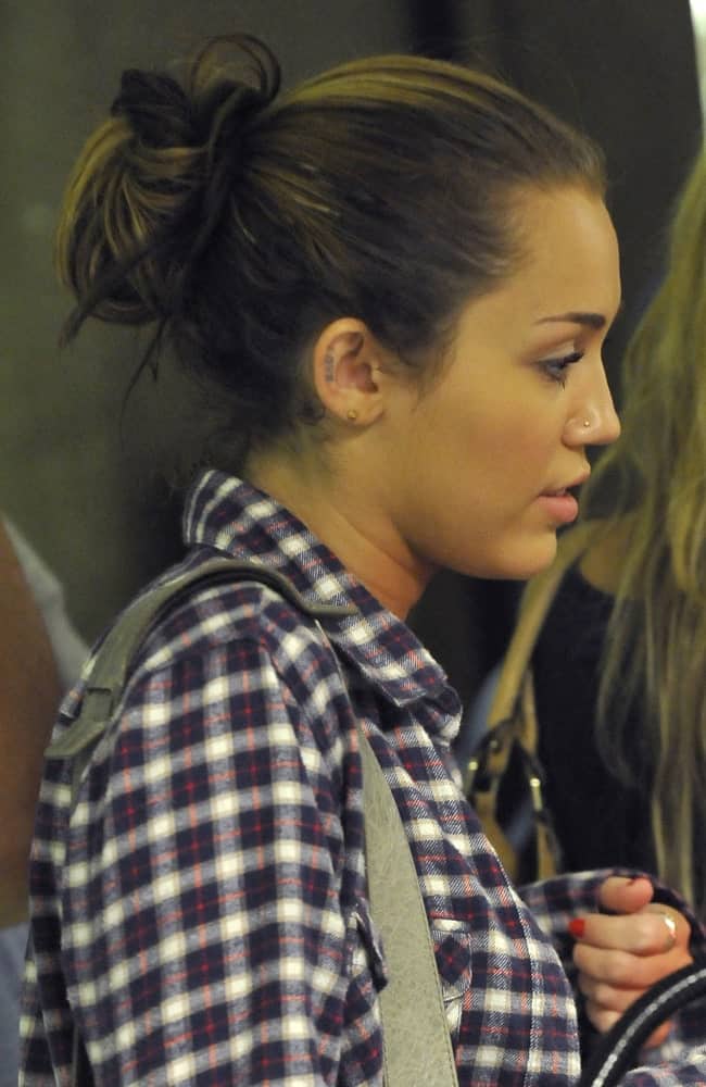 Popstar Miley Cyrus was seen at LAX on June 14, 2010 in Los Angeles, California. She was seen in her plaid shirt, simple make-up and a messy highlighted bun with tendrils.