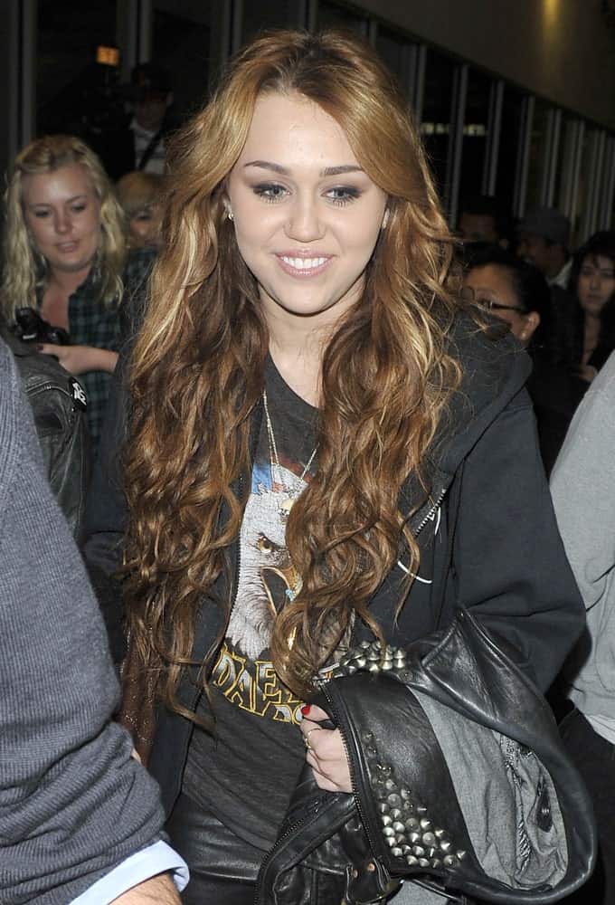 Actress/singer Miley Cyrus was seen at LAX airport on April 8, 2011 in Los Angeles, California. She paired her casual black shirt and black leather jacket with a long curly layered hairstyle that is center-parted.