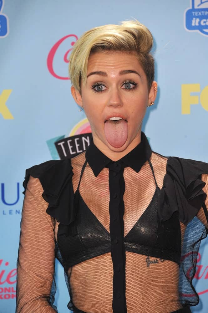 Miley Cyrus wore a black sheer outfit to show her black leather bikini top underneath that went quite well with her side-swept highlighted undercut pixie hairstyle at the 2013 Teen Choice Awards at the Gibson Amphitheatre, Universal City, Hollywood. August 11, 2013 Los Angeles, CA.