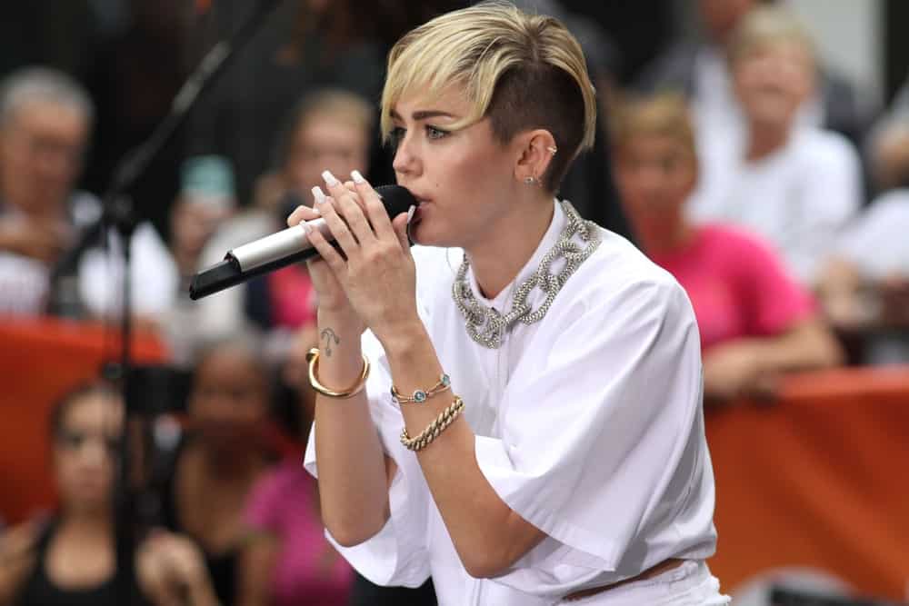 Miley Cyrus performed on NBC's Today Show at Rockefeller Plaza on October 7, 2013 in New York City. She paired her white button-down shirt with a blond highlighted undercut pixie hairstyle with gorgeous bangs.