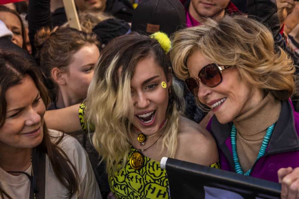 On January 21, 2017, Miley Cyrus and Jane Fonda participated in the Women's March, 750,000 activists protesting Donald J. Trump the day after Presidential Inaugural in Los Angeles. Miley went with a yellow dress to go with her side-swept wavy balayage hairstyle.
