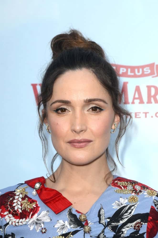 Rose Byrne was at the "Peter Rabbit" Premiere at the Pacific Theaters at The Grove on February 3, 2018 in Los Angeles, CA. She wore a lovely colorful and floral dress and topped it with a highlighted raven top knot bun hairstyle with loose tendrils.
