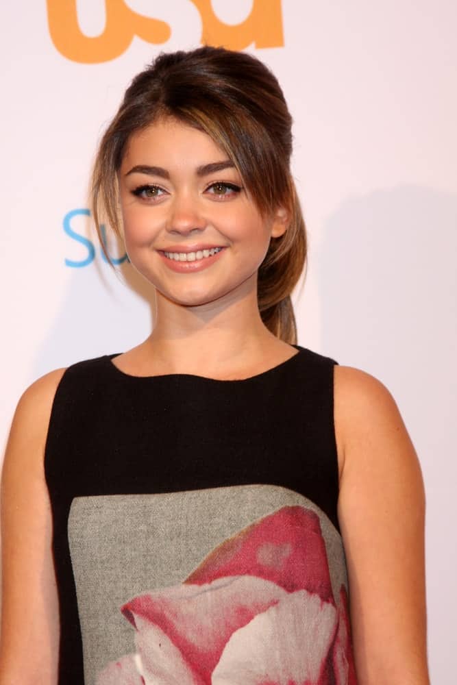 Sarah Hyland was at the Modern Family on USA Network Fan Appreciation Event at Village Theater on October 28, 2013 in Westwood, CA. She wore a simple yet lovely black dress that she paired with a highlighted ponytail hairstyle with loose bangs.