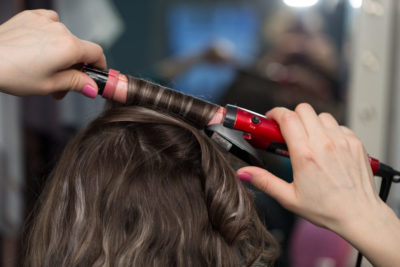 Woman getting hair curled by hair stylist