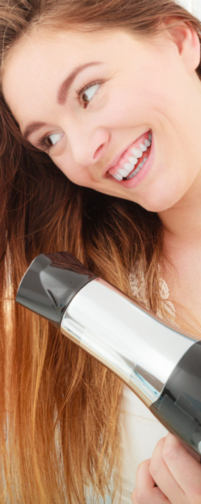 Young woman blow drying her hair