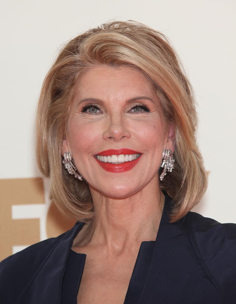 In this fourteenth hairstyle modeled by actress Christine Baranski, the style features a honey blonde color that is complement by different-length cut-in layers curled both inwards towards the face and away from the face in order to add dimension and volume. The style also features a messy combed over side-part on the left side of the head.