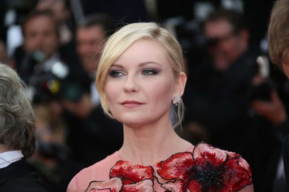 If you have a layered haircut, you can create your bangs to suit the occasion. As Kirsten Dunst demonstrates, pull your hair back in a tight updo and swoop your longer front layer to the side of your face for a dramatic and posh effect. This removes the severity of the bun and gives a volumizing effect to your hair.