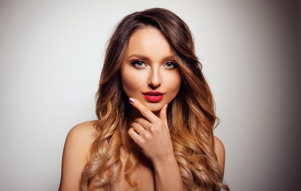 This young woman sports a balayage that graduates from a dark, rich caramel color to a golden honey and copper shade. It’s a perfect look with long loose curls.