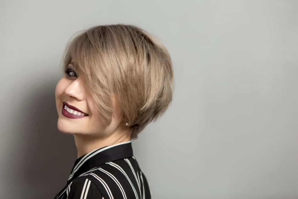 This young woman’ short brown hair is balanced with extra-long bangs in the front, falling freely over her eyes. This particular hairstyle gives her a very K-pop boy band member look.