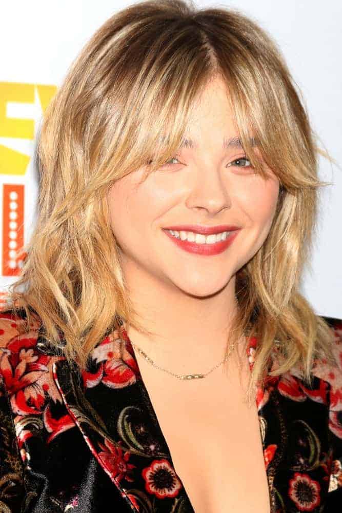 Chloe Grace Moretz was at the TrevorLIVE Los Angeles 2016 at Beverly Hilton Hotel on December 4, 2016, in Beverly Hills, CA. She wore a colorful floral smart casual outfit with her shaggy sandy blonde hairstyle with layers and eye skimmer bangs.
