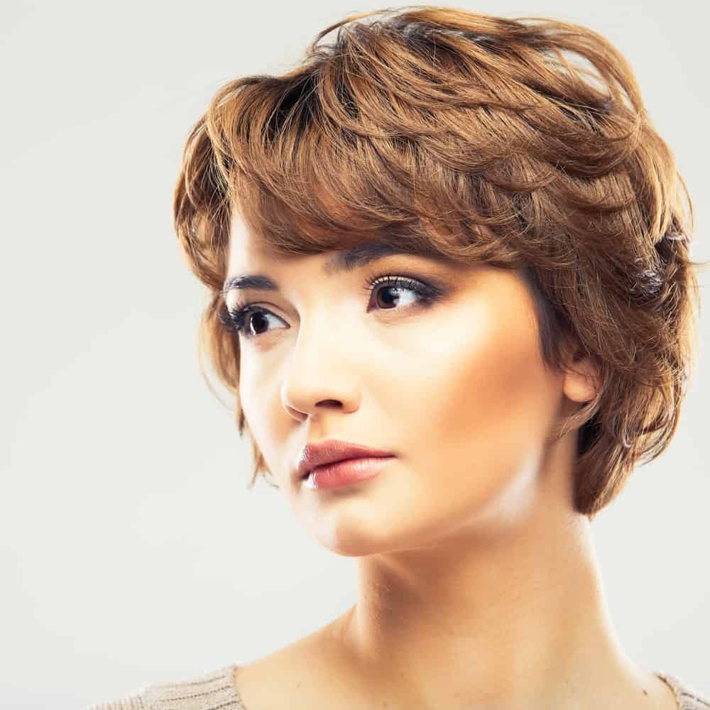 The pixie hairstyle is all the rage these days. The look that was first iconized by Mia Farrow in “Rosemary’s Baby” is back in style, thanks to actresses like Ginnifer Goodwin and Emma Watson. This young model is rocking a feathery version, sporting a heedful of layered, light brown locks. The style gives her a very youthful look. Another plus point of a volumizing pixie cut is that it can be styled in many ways, including curls.