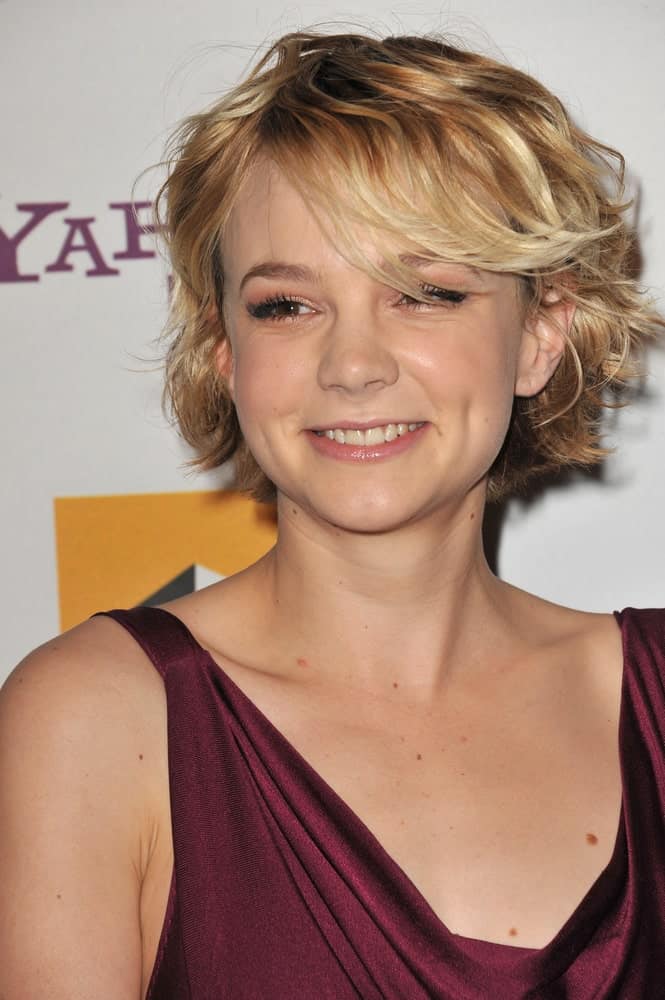 The young and lively Carey Mulligan is seen in a mesmerizing layered bob haircut for women. Notice the remarkable streaks that transform from deep chestnut brown at the roots to pale blonde at the tips. Long, side-swept bangs casually cover the forehead while the uneven layers are maintained throughout the hair to give a relaxed and easy-going look. 