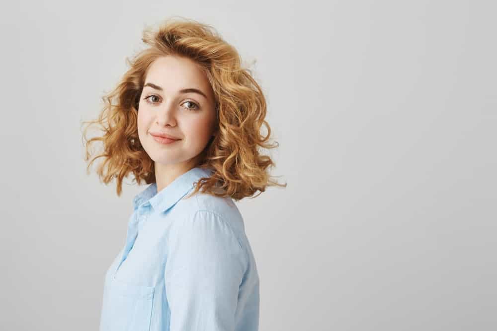 This is a classic curly, short hairstyle with a side parting and a blend of tight-loose curls that look simply beautiful. The gorgeous light brown hair dye seems to further accentuate the curly look.