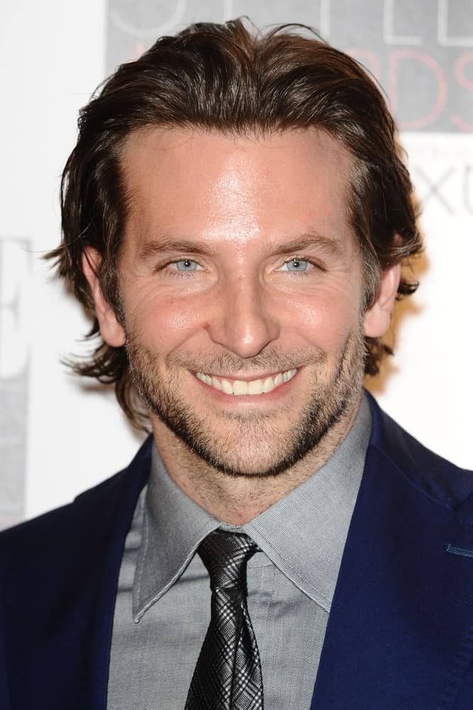Even though he is a phenomenal actor, one of Bradley Cooper’s biggest claims-to-fame is his thick brown voluminous waves of hair. The “A Star is Born” actor is one of the few Hollywood actors who sports shoulder-length hair and rocks it. On red carpet events, Cooper often styles his hair in a wet look by adding styling product to his wavy locks and pushing them back away from his forehead. The style further highlights the actor’s prominent cheekbones and piercing eyes.