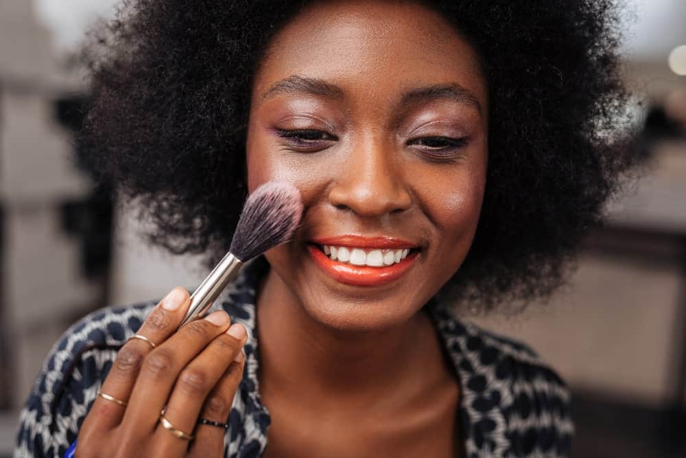 Woman applying rogue or blush.