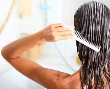 A woman applying hair conditioner to her wet hair