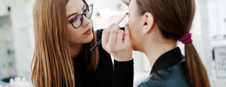 A makeup artist applies eyeshadow on a woman.