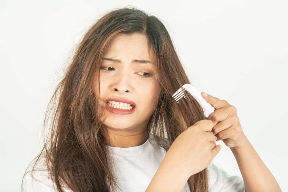 A woman trying to comb rough hair 