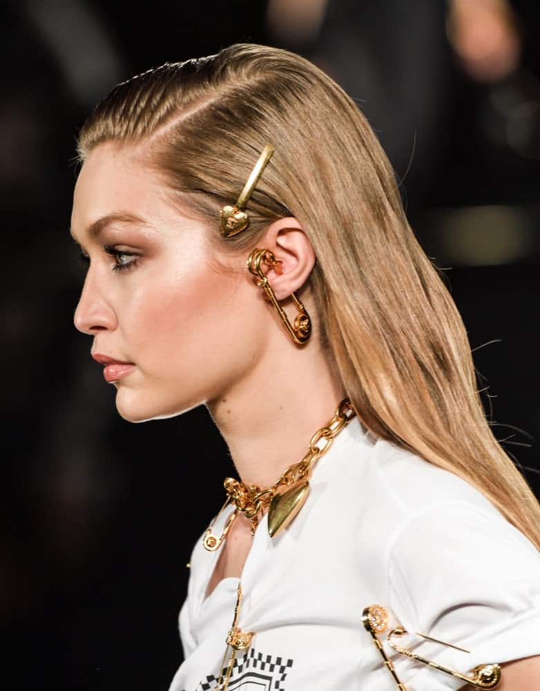 On December 2, 2018, Gigi Hadid walked runway at the Versace Pre-Fall 2019 Collection at The American Stock Exchange. Her hair was styled with pins into a slick half up hairstyle with subtle highlights.