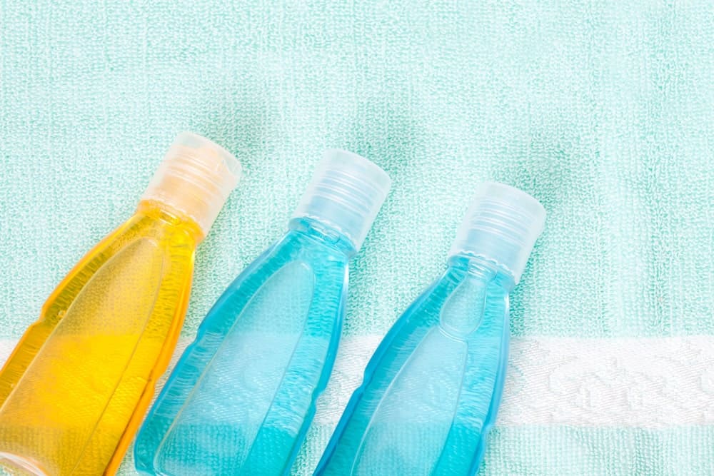 Three bottles of shower gel, on top of a green towel.