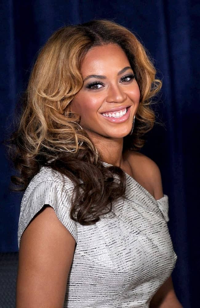 Beyonce Knowles is picture-perfect with her highlighted middle part curls at a public appearance for The Beyonce Cosmetology Center Grand Opening held on March 5, 2010.