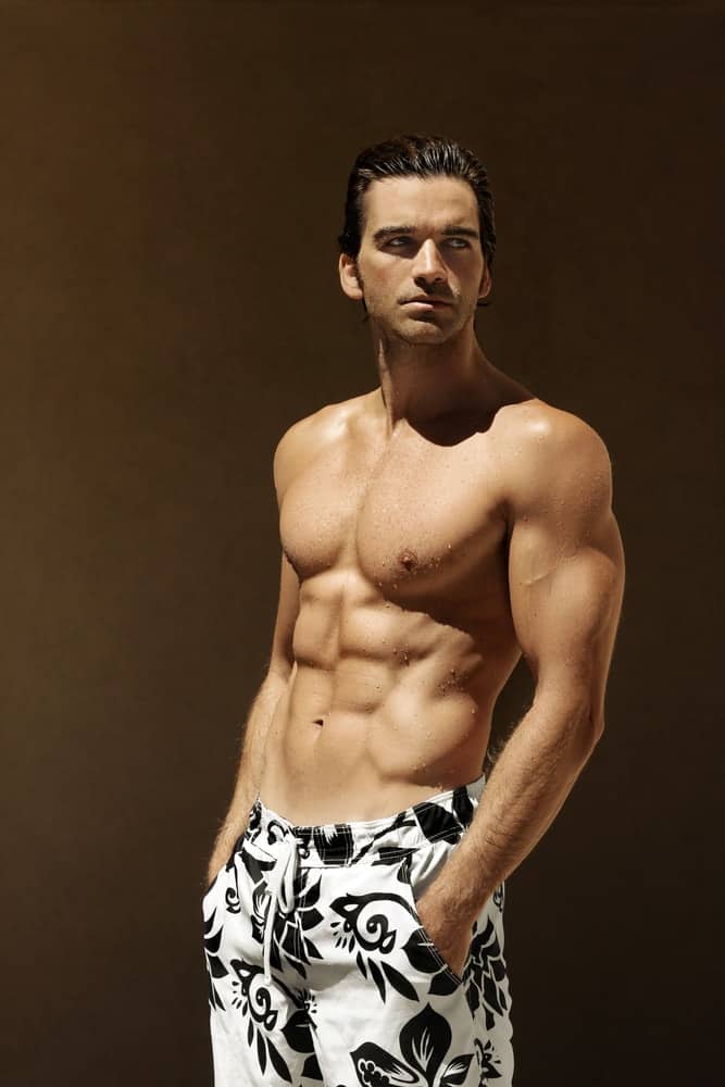 A man wearing a pair of floral swimming board shorts.