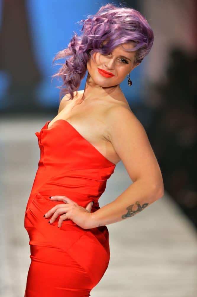 Kelly Osbourne looking stunning with the purple hair and the red dress. She’s posing on the runway at The Heart Truth’s Red Dress Collection on the 6th of February 2013.