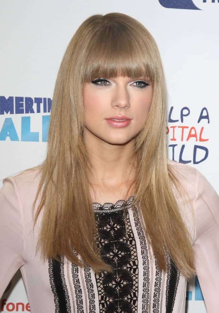Taylor Swift resembles like a barbie with her straight layered hair incorporated with blunt bangs. This was taken at the Capital FM Summertime Ball – Media Room on June 9, 2013.
