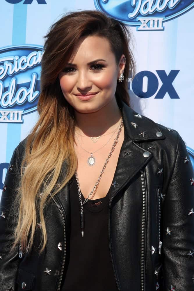 Demi Lovato wore a cool black leather jacket to complement her long side-swept highlighted tousled hairstyle with a shaved side and long side-swept bangs at the American Idol Season 13 Finale at Nokia Theater at LA Live on May 21, 2014, in Los Angeles, CA.