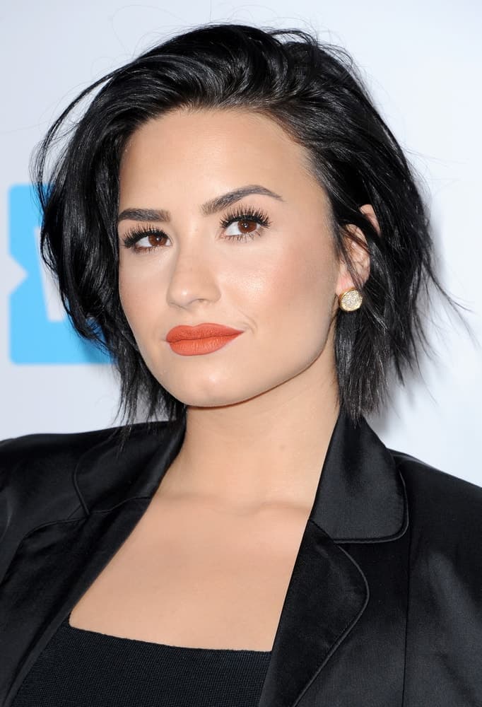 Demi Lovato’s short raven hair was tossed up for a tousled side-swept finish to match with her black outfit at the WE Day California held at The Forum in Inglewood, USA on April 7, 2016.