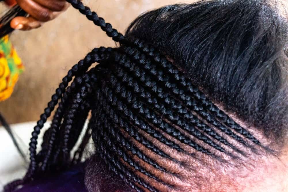 A close look at a woman having her hair braided.