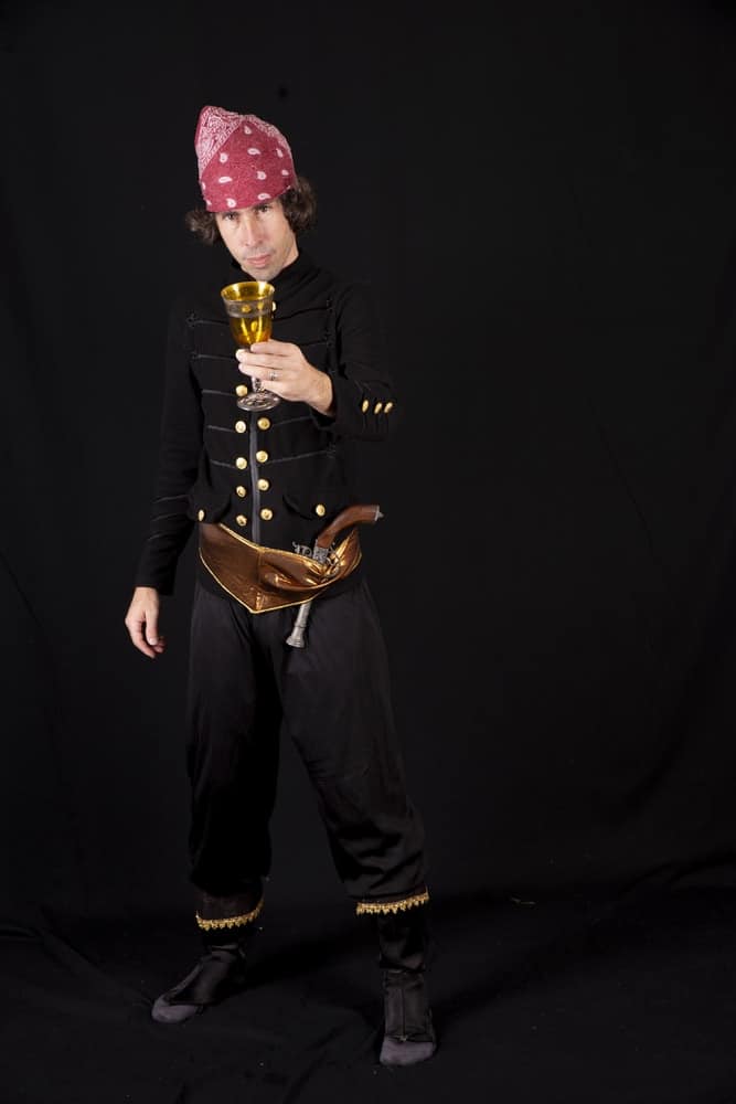 A man wearing a black pirate costume with a matching pirate headband.